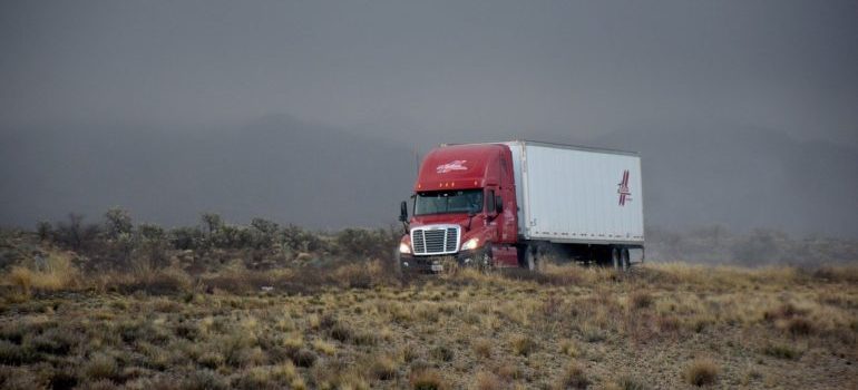 A truck with a logo on it driving down a road.