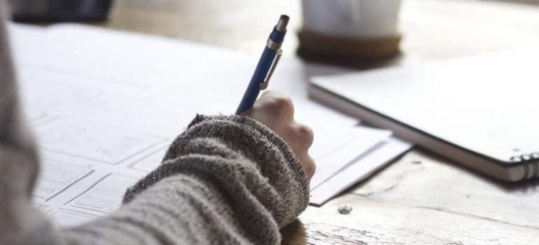 A girl writing on a piece of paper while considering outdoor advertising ideas for movers.