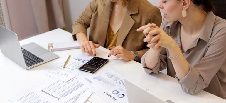 Two colleagues doing calculations and trying to figure out how much companies pay for advertising