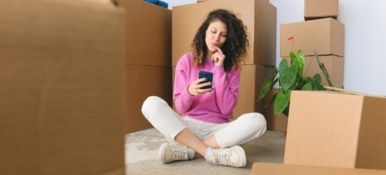 A person surrounded by boxes using a smartphone