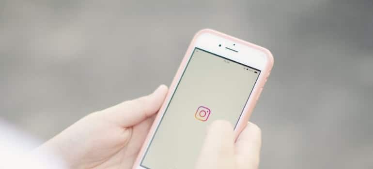 Person holding a smartphone and using Instagram, one of the best places to advertise a company